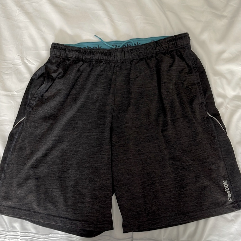 Mens Reebok athletic shorts in dark gray with inside teal waistband. 21.5” L.